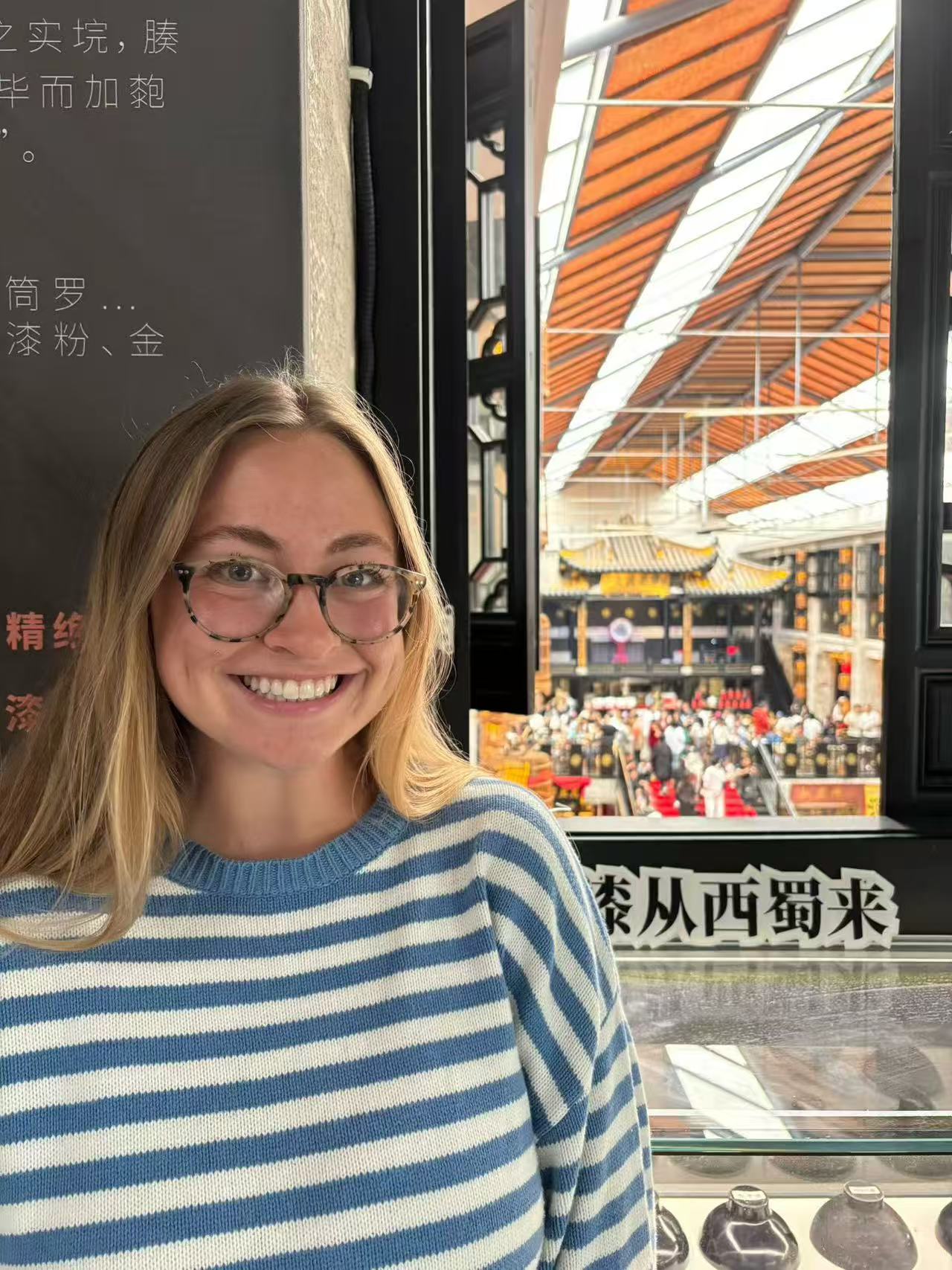 A smiling guest beside a window overlooking a busy indoor market.