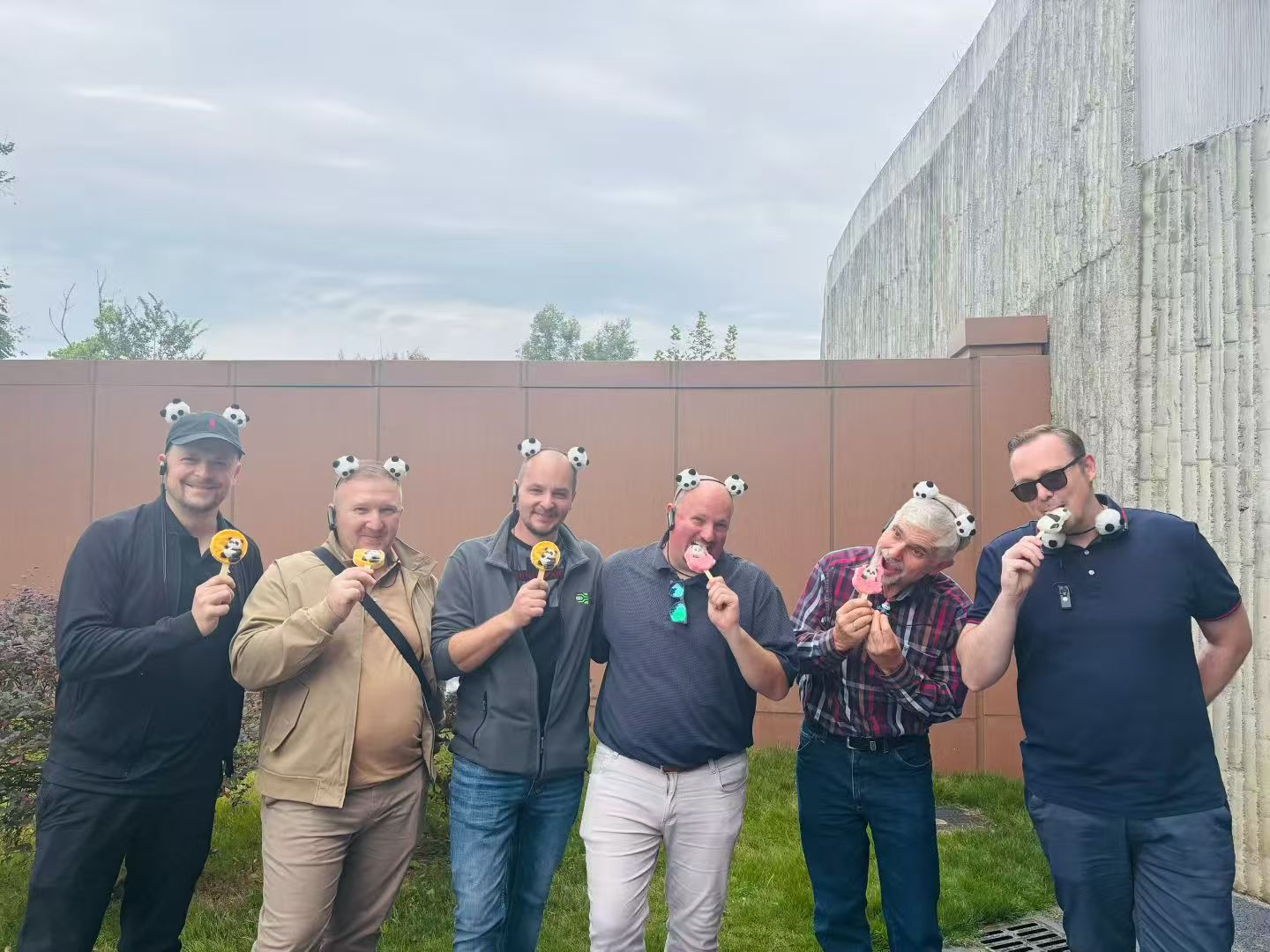 Six guests outdoors holding panda-themed treats and wearing small panda headbands.